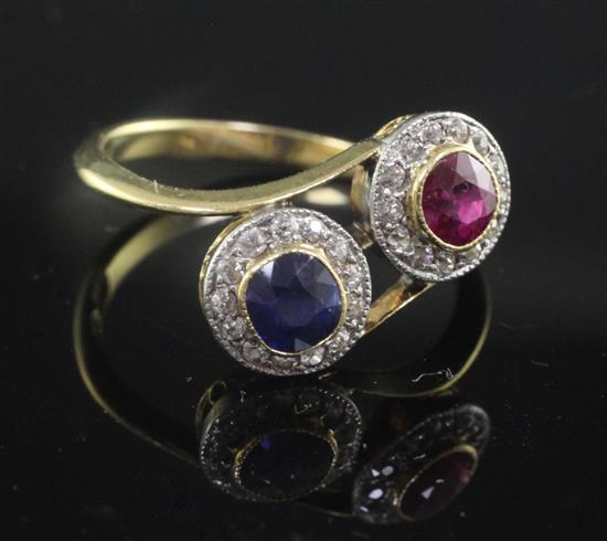 A mid 20th century 18ct gold, ruby, sapphire and diamond double cluster crossover ring, size P.